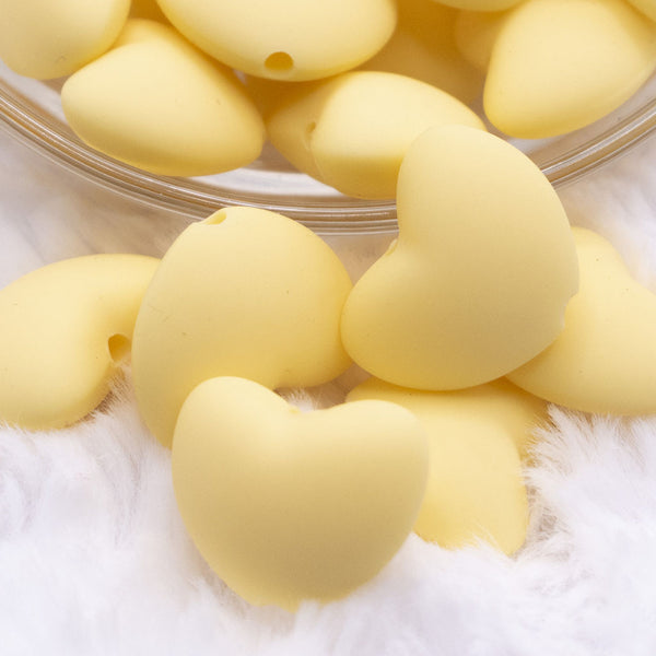 Close up view of a pile of 20mm Light Yellow heart silicone bead