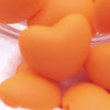 Close up view of a pile of 20mm Orange heart silicone bead