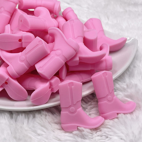 front view of a pile of Pink Cowboy Boot Silicone Focal Bead Accessory - 30mm x 26mm