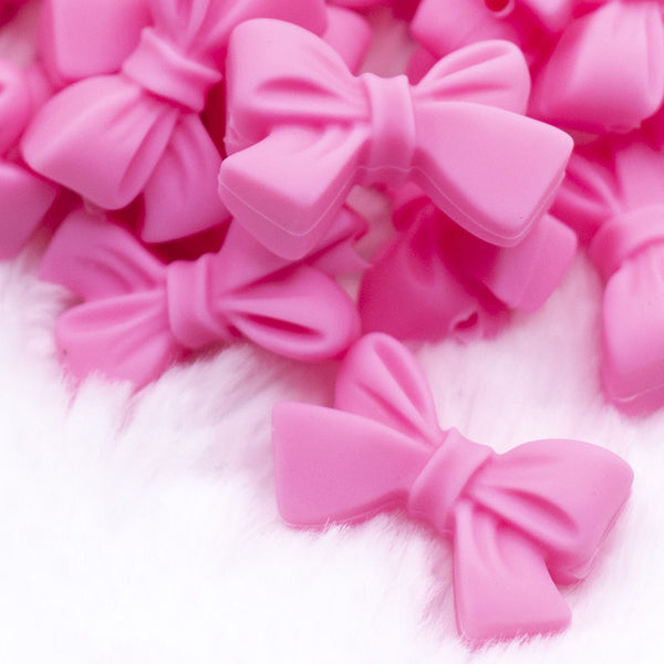 Close up view of a pile of 27mm Pink Bow Knot silicone bead