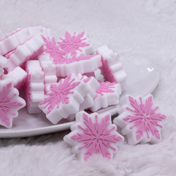 front view of a pile of Pink Snowflake Silicone Focal Bead Accessory - 28mm x 28mm