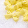 Close up view of a pile of 27mm Yellow Bow Knot silicone bead